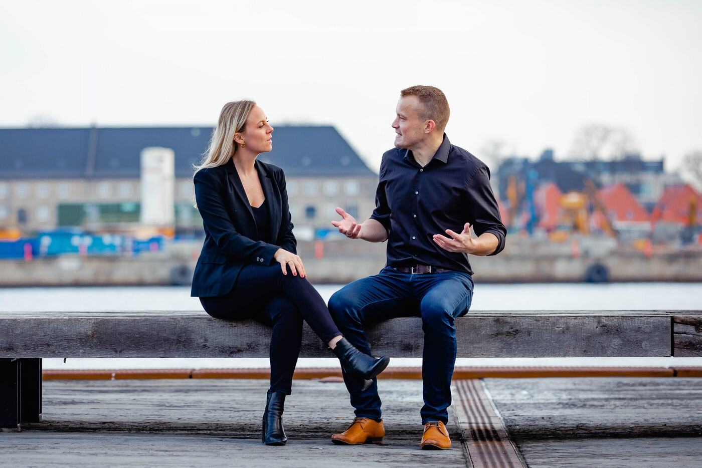 Thomas Jørgensen i samtale med en kvinde på en bænk ved havnen