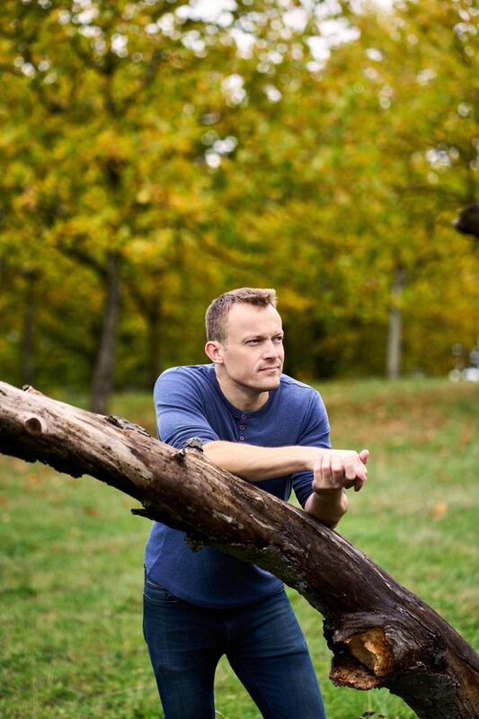 Thomas Jørgensen lænet op ad en træstamme, eftertænksom